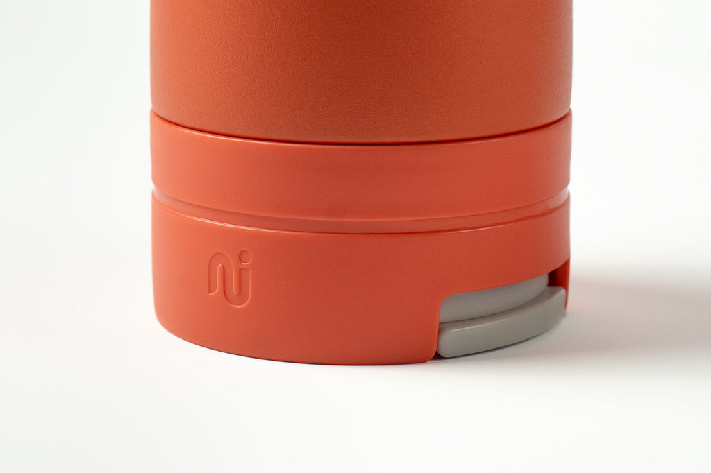 Close-up of a coral Duet coffee cup with a light grey lid tucked into the base, on a white background.