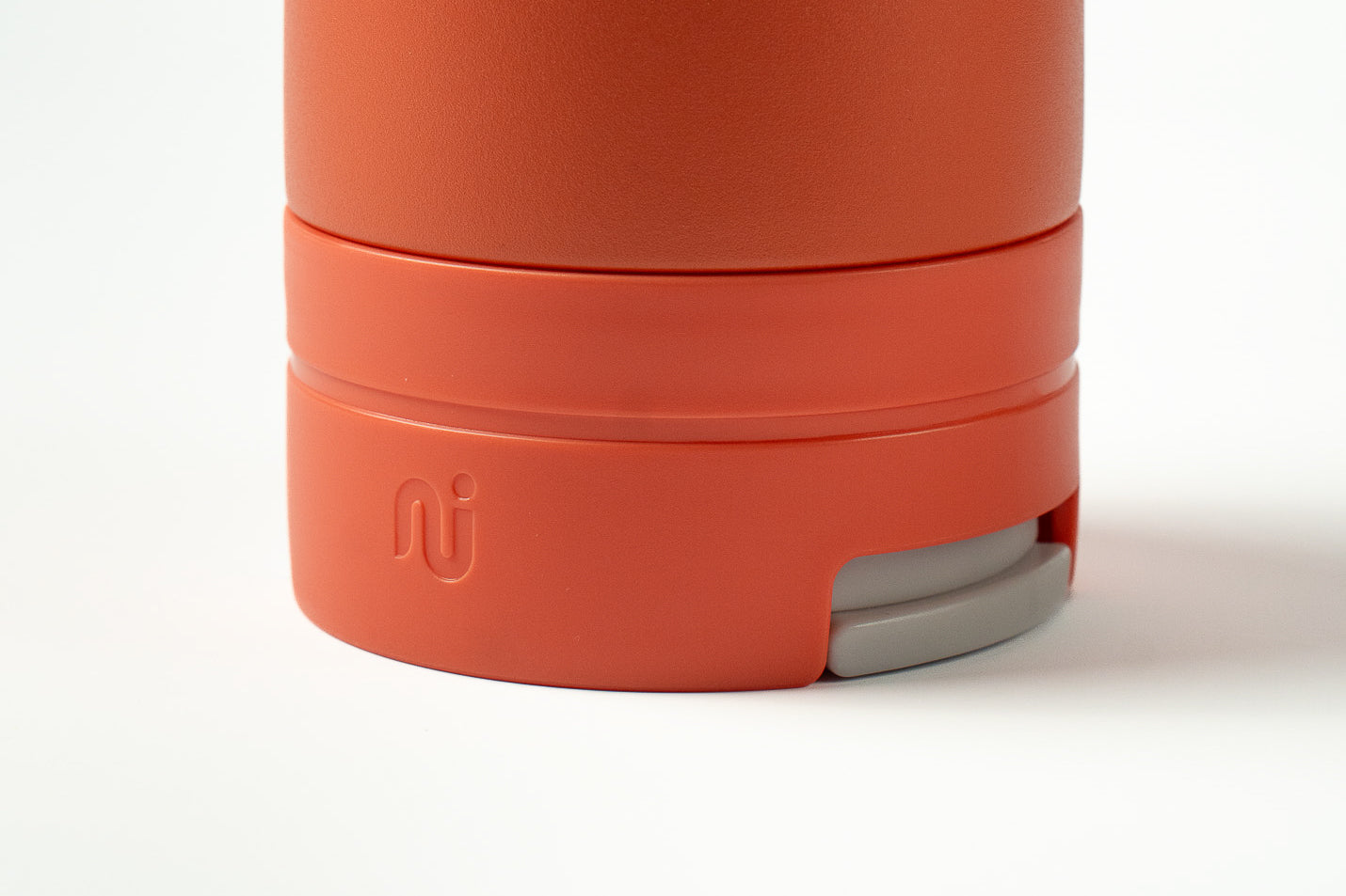 Close-up of a coral Duet coffee cup with a light grey lid tucked into the base, on a white background.